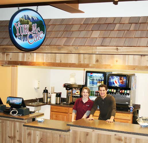 Female and male employee posing behind the concession counter at Rocket Ice Skating rink.