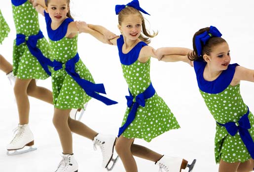 Synchronized ice skating starfire team in green uniforms performing