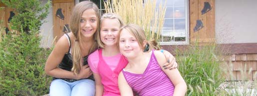 Three Girls in a summer group outing relaxing on a rock outside of Rocket Ice Skating Rink