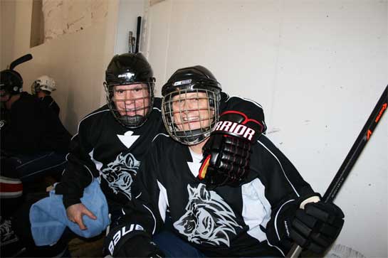 Two over 50 year old men sitting on bench during an adult hockey league game