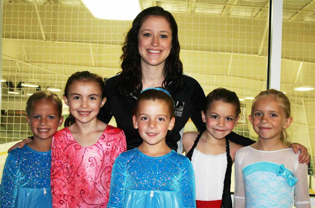 Female coach and her figure skaters at the basic skills ice skating competition.